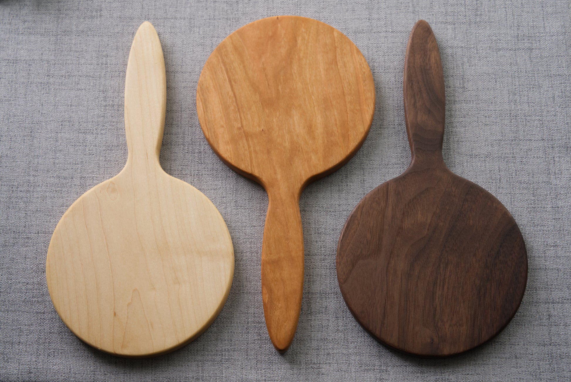 Wood Hand mirrors showing the 3 wood varieties available. From left to right there is Hard maple, Cherry and Black Walnut. 